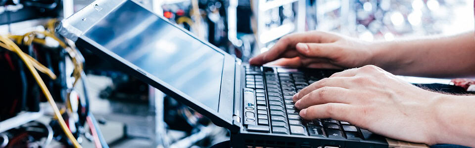 IT specialist working on computer in bitcoin and crypto currency mining farm.