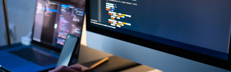 Mobile developer writes program code on a computer, programmer work in home office.