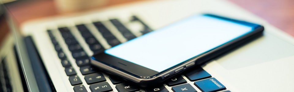 Smart phone on laptop computer in coffee shop